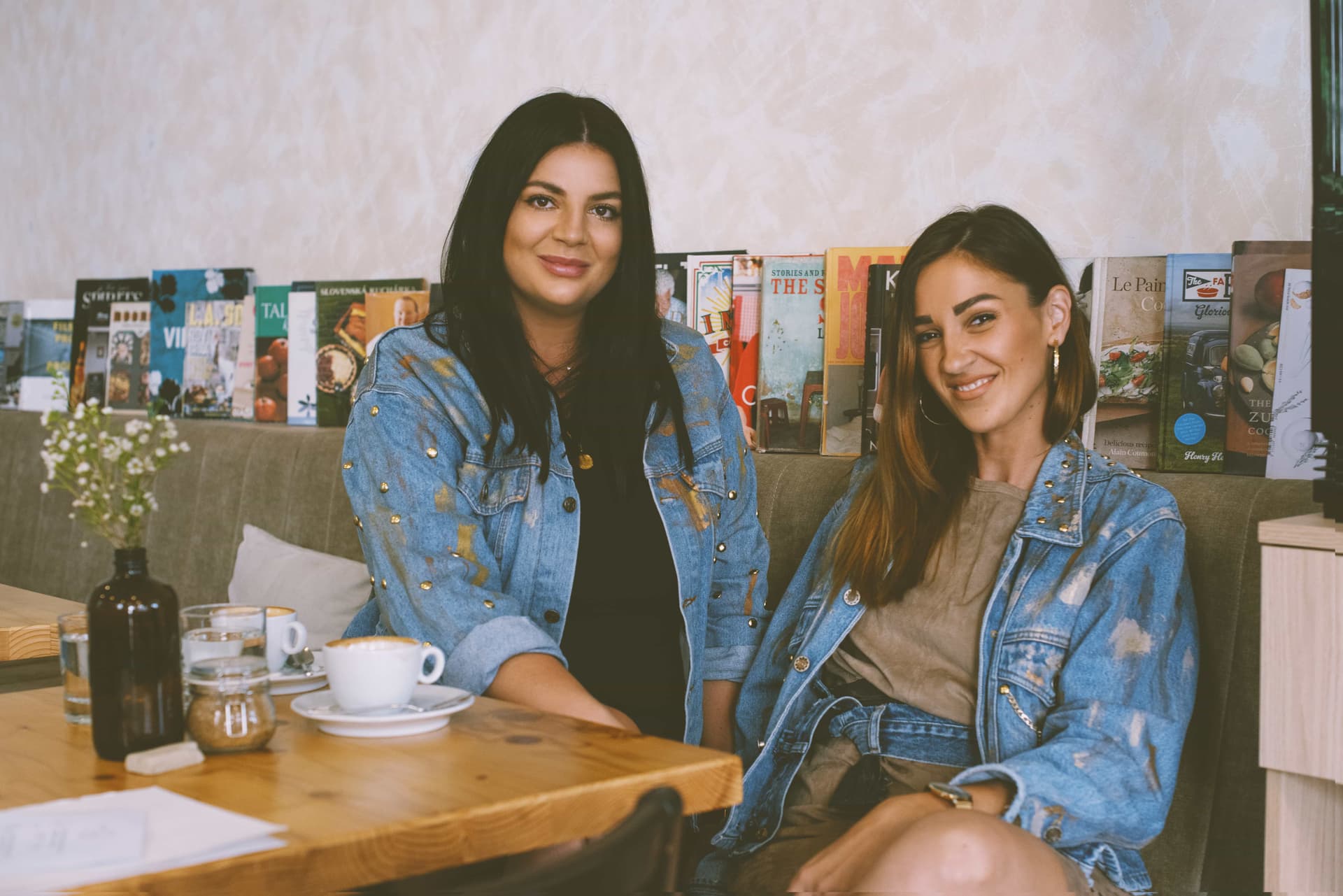 Two women in denim jackets sitting at a table